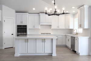 Kitchen featuring light hardwood / wood-style floors, a center island, white cabinets, and stainless steel appliances