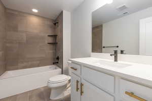 Full bathroom with tiled shower / bath combo, tile patterned floors, toilet, and vanity