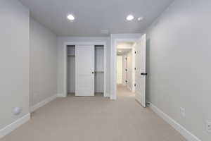 Unfurnished bedroom with light carpet and a closet