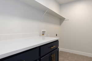 Clothes washing area featuring electric dryer hookup, cabinets, hookup for a washing machine, and light tile patterned floors