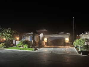 View of front of house with an attached garage, stucco siding, driveway, and a tile roof