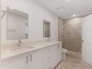 Bathroom featuring dual vanity, tile patterned floors, a shower with shower door, and toilet