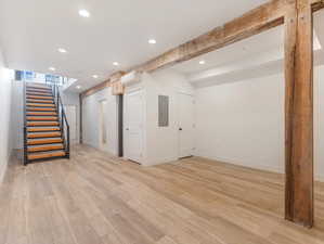 Basement with a wall mounted AC, light hardwood / wood-style floors, and electric panel