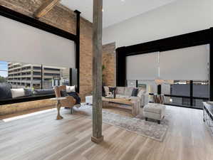 Living room featuring brick wall, light hardwood / wood-style floors, and a towering ceiling