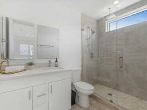 Bathroom with vanity, toilet, walk in shower, and tile patterned flooring