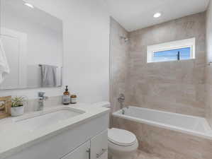 Full bathroom featuring tiled shower / bath combo, vanity, and toilet