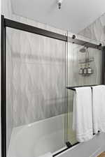 Bathroom featuring shower / bath combination with glass door and a textured ceiling