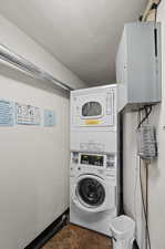 Clothes washing area featuring stacked washer / dryer and dark tile patterned flooring