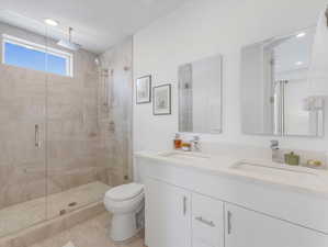 Bathroom featuring double vanity, walk in shower, tile patterned flooring, and toilet