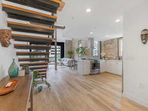 Kitchen featuring white cabinetry, light hardwood / wood-style flooring, tasteful backsplash, stainless steel range with gas cooktop, and wall chimney exhaust hood