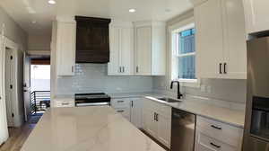 Kitchen featuring sink, light wood-type flooring, stainless steel appliances, and light stone countertops