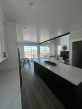 Kitchen with stainless steel refrigerator, a fireplace, a kitchen island, and dark hardwood / wood-style flooring