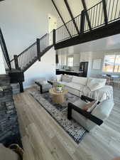 Living room featuring wooden ceiling, high vaulted ceiling, sink, light hardwood / wood-style floors, and beam ceiling