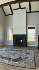 Unfurnished living room featuring hardwood / wood-style flooring, beamed ceiling, a wealth of natural light, and high vaulted ceiling