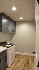 Washroom with washer / dryer, light hardwood / wood-style flooring, and cabinets