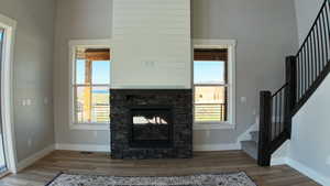 Living room featuring a stone fireplace, a high ceiling, and light hardwood / wood-style flooring