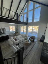 Living room with hardwood / wood-style floors, beamed ceiling, and high vaulted ceiling