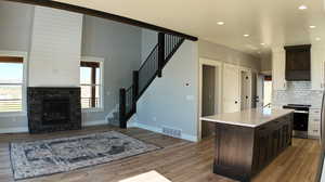 Kitchen with a fireplace, wood-type flooring, backsplash, and dark brown cabinetry