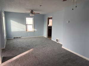 Carpeted spare room featuring ceiling fan and a textured ceiling