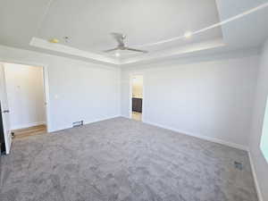 Carpeted spare room with ceiling fan and a raised ceiling