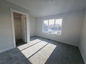 Unfurnished bedroom featuring dark colored carpet and a closet