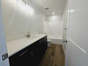 Full bathroom featuring hardwood / wood-style floors, vanity, toilet, and shower / tub combination