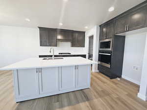 Kitchen with stainless steel appliances, tasteful backsplash, sink, and light wood-type flooring