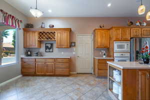 Kitchen  and dining featuring decorative light fixtures, light tile patterned floors, white appliances & custom rustic maple buffet & wine rack