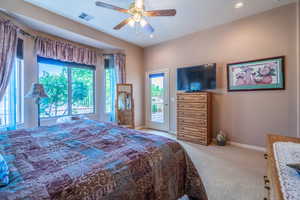 Owner Bedroom #1 with light colored carpet, access to outside, and ceiling fan