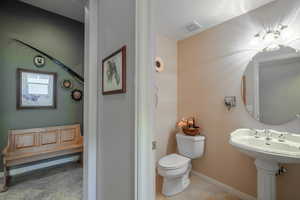 Half Bathroom off of entry hall with tile patterned floors and toilet