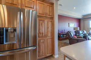 Kitchen featuring a tray ceiling, light tile patterned floors, and stainless steel refrigerator with ice dispenser & pantry cabinets