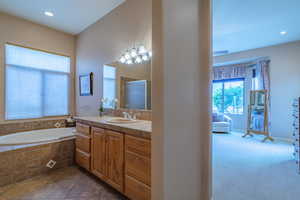 Owner Bathroom #1 with vanity, tile patterned floors, and a relaxing tiled tub