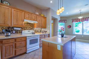 Kitchen with white electric range, pendant lighting, a center island, light tile patterned floors, and backsplash