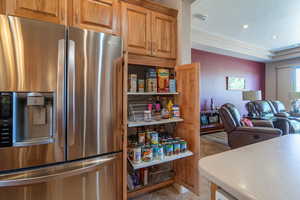 Kitchen with stainless steel fridge with ice dispenser and light tile patterned floors & Roll-out Shelves in Pantry