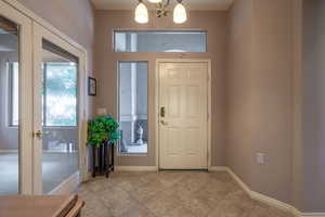 Tiled entryway featuring a notable chandelier and a healthy amount of sunlight from transom window & sidelight