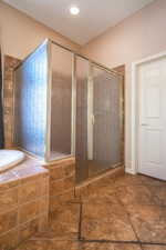 Bathroom with shower with separate bathtub and tile patterned floors