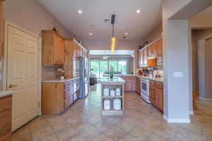 Kitchen & Dining with light tile patterned flooring, backsplash, a center island, hanging light fixtures, and appliances with stainless steel finishes