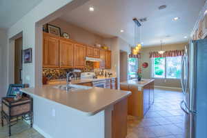 Kitchen with stainless steel fridge, electric range oven, sink, kitchen peninsula, and backsplash