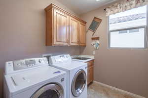 Washroom with cabinets, independent washer and dryer, sink, and light tile patterned floors