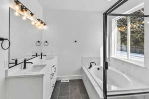 Bathroom with double vanity, tiled bath, and tile patterned floors