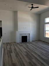 Unfurnished living room featuring hardwood / wood-style flooring, a tiled fireplace, and ceiling fan