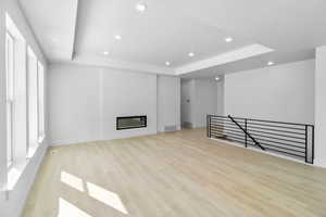 Unfurnished living room with light hardwood / wood-style flooring and a tray ceiling