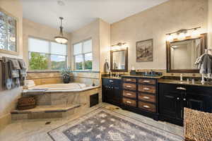 Bathroom featuring double vanity, tile patterned flooring, and tiled bath