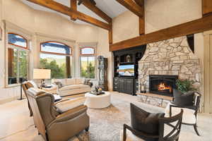 Living room with beamed ceiling, a fireplace, light colored carpet, and a high ceiling