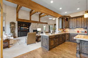 Kitchen with a fireplace, kitchen peninsula, dark brown cabinetry, decorative backsplash, and light carpet