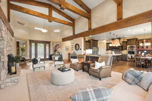 Living room with an inviting chandelier, light hardwood / wood-style flooring, and high vaulted ceiling