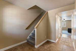 Stairs with ceiling fan and tile patterned flooring