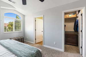 Bedroom with a closet, light colored carpet, lofted ceiling, a walk in closet, and ceiling fan