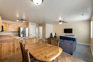 Tiled dining area with rail lighting, sink, and ceiling fan