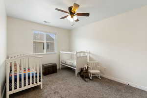 Carpeted bedroom with a nursery area and ceiling fan